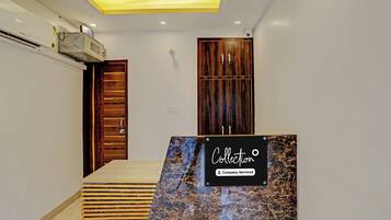A hotel reception area with a marble counter, wooden doors, and a ceiling with recessed lighting.