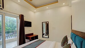 Une chambre d’hôtel avec un lit, un bureau, un miroir et une télévision.
