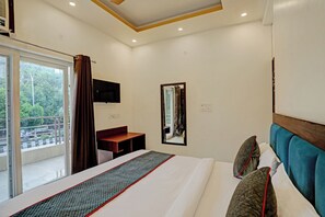 Una habitación de hotel con cama, escritorio, espejo y televisión.