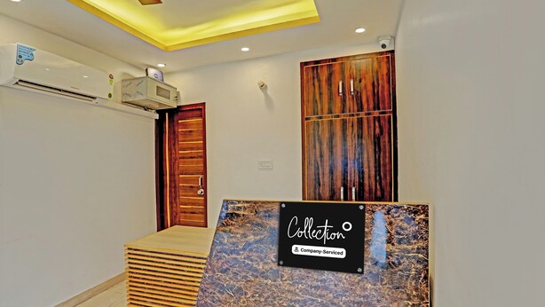 A reception area with a wooden reception desk, a wall-mounted air conditioning unit, and a sign indicating the area is company-serviced. - Super Collection O Sector 55 Noida (Noida)