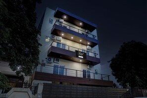 Un edificio de varios pisos con balcones, unidades de aire acondicionado y un letrero que indica que cuenta con servicio de empresa.