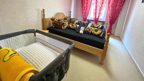 A room with a bed, a small table, and a window with curtains. - Spacious Apartment With Balcony (Boppard)