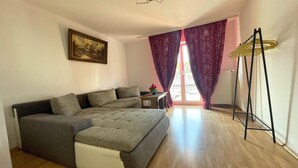 A room with a sofa bed, a small table with a vase, and a radiator. - Spacious Apartment With Balcony (Boppard)