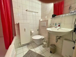 A bathroom with a toilet, sink, shower, and a radiator. - Spacious Apartment With Balcony (Boppard)