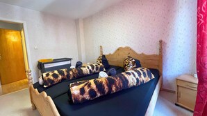 A bedroom with a wooden bed, a nightstand, a desk, and a red curtain. - Spacious Apartment With Balcony (Boppard)