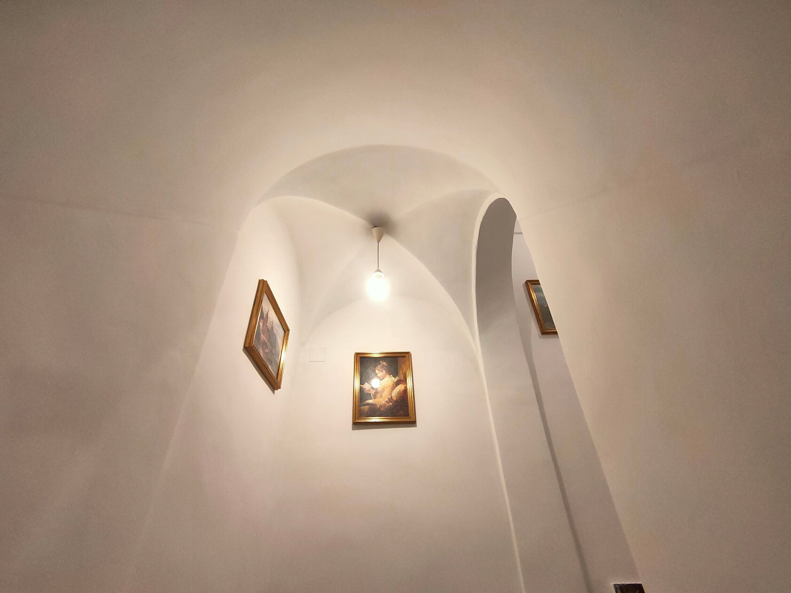 Techo con tres obras de arte enmarcadas y una lámpara.