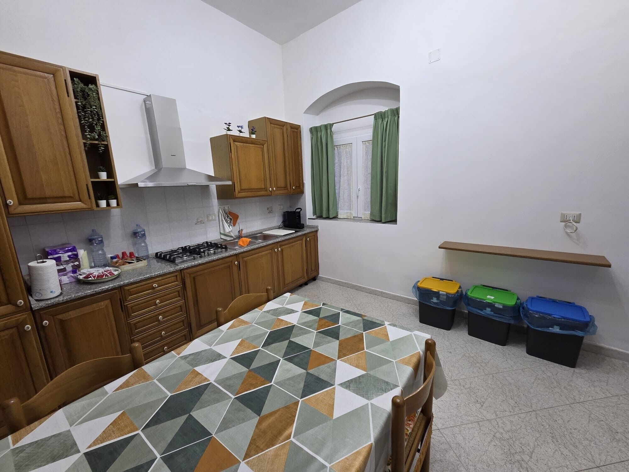 Una cocina con gabinetes de madera, estufa a gas y piso de baldosas.