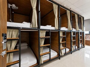 A row of bunk beds with curtains, a fan, and a control panel. - Top Of The Loop Hostel Ha Giang (Ha Giang 1)