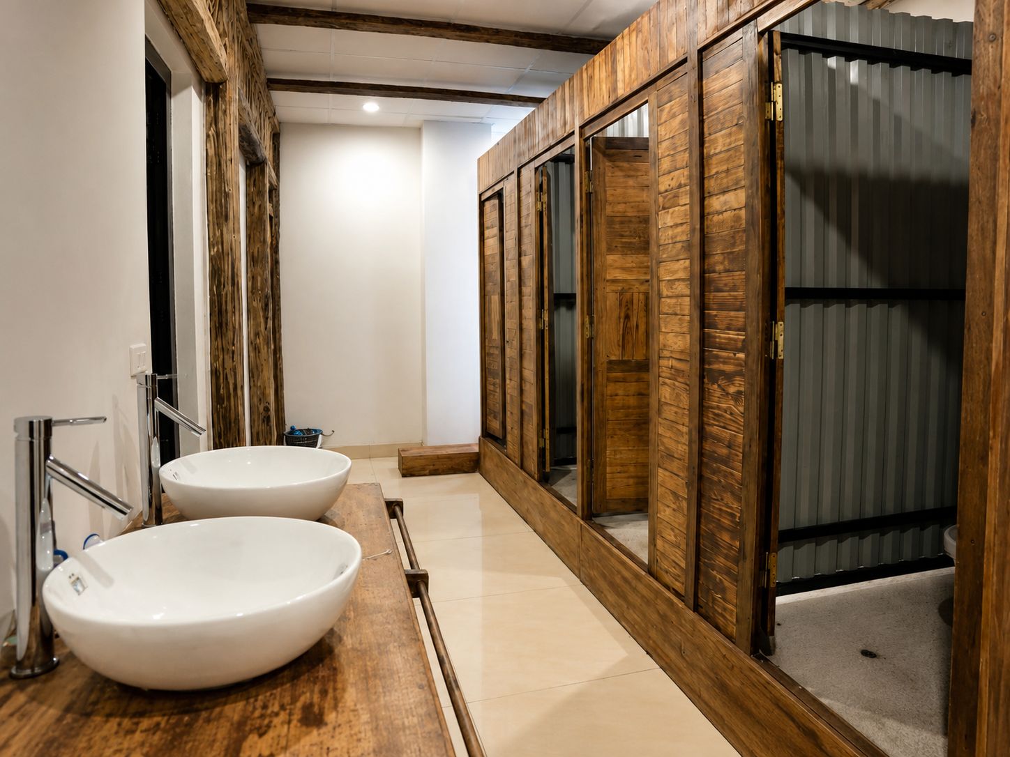 Une salle de bain moderne avec deux grands lavabos blancs, un lambris en bois et une porte en métal.