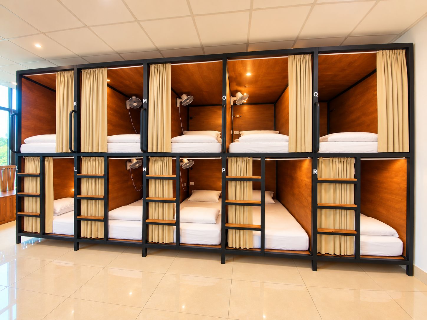 Habitación con literas, paredes de madera y cortinas; cada litera con una almohada y una mesita de noche.