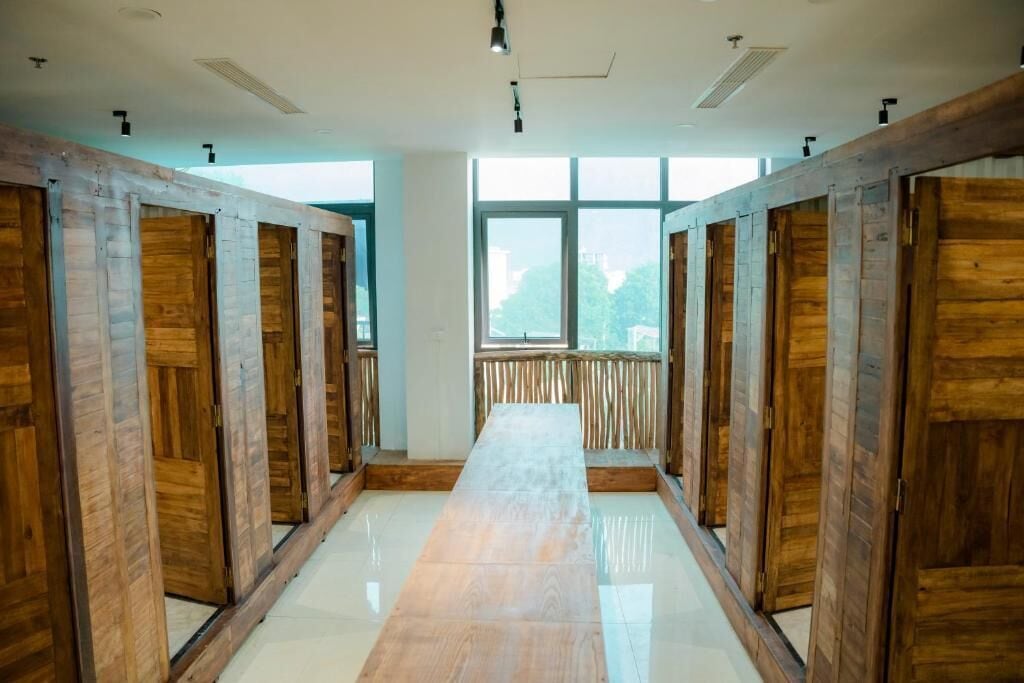 A row of wooden doors leading to individual rooms, a central hallway, and a large window with a view.