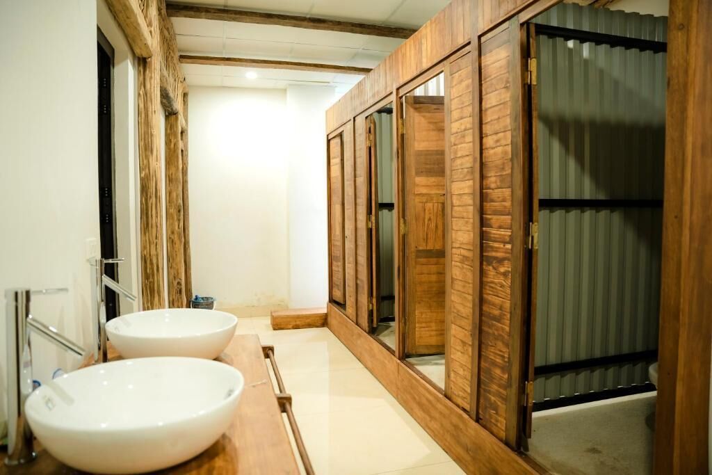 A narrow bathroom with wooden paneling, two white sinks, and a mirror.