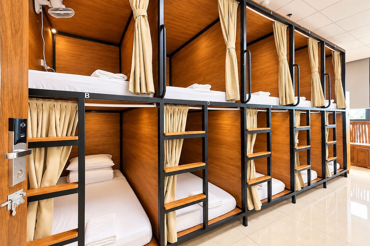 A hotel room with bunk beds, wooden paneling, and curtains.