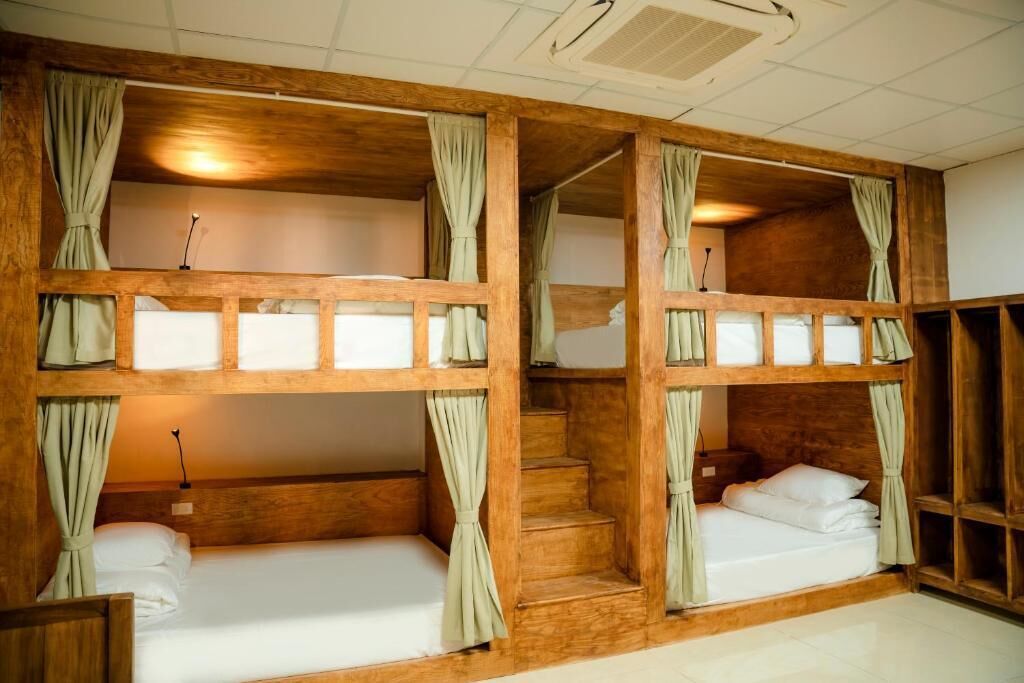 Een kamer met stapelbedden, houten hoofdeinden en gordijnen.