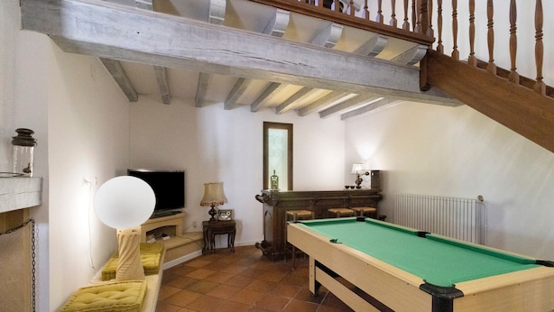 Una habitación con mesa de billar, televisión y escalera.