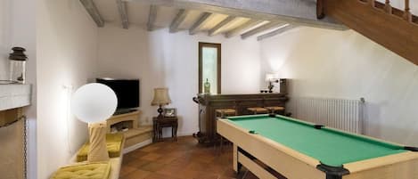 Una habitación con mesa de billar, televisión y escalera.