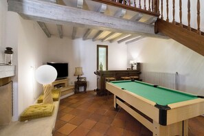 Una habitación con mesa de billar, televisión y escalera.