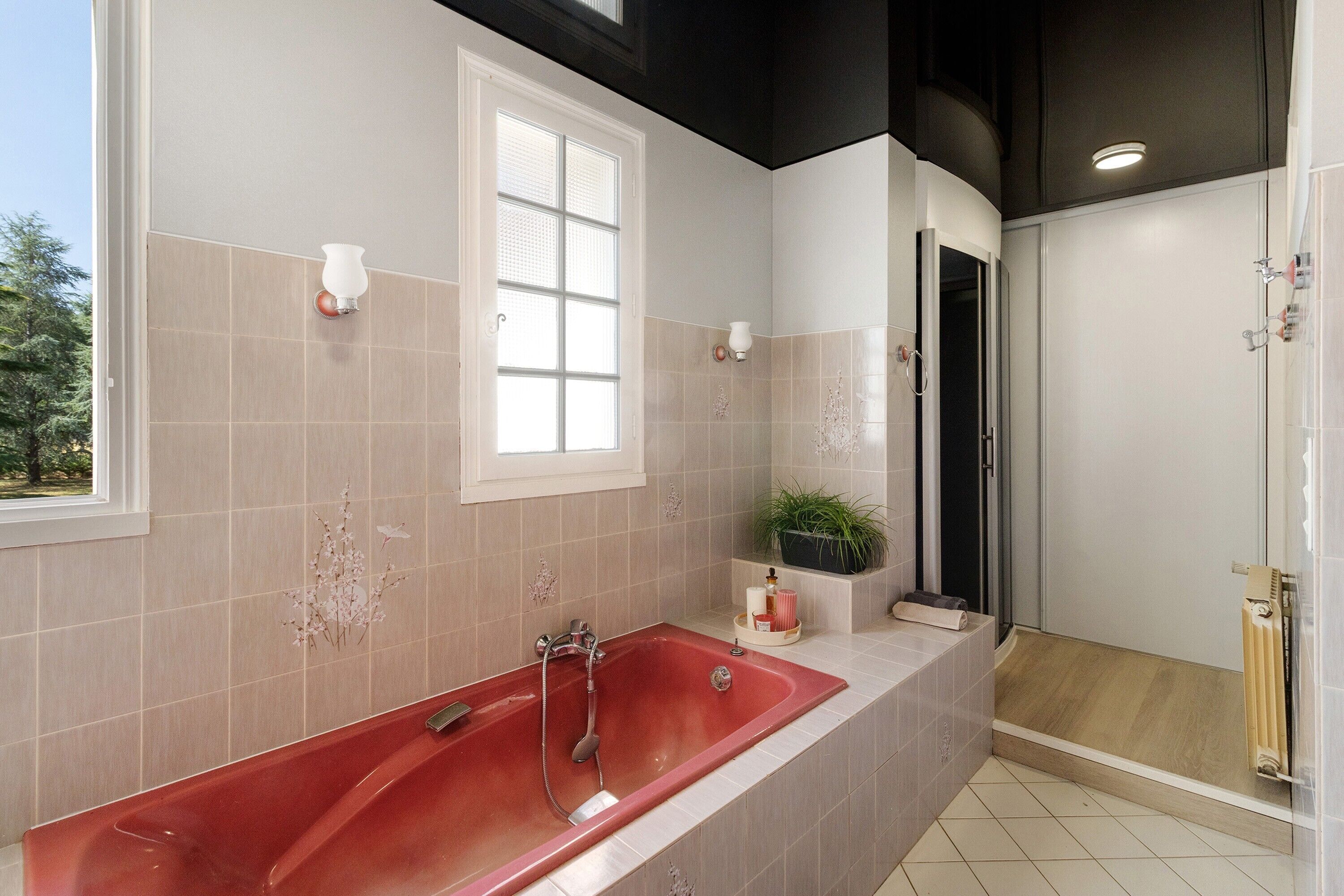 Une salle de bain moderne avec une baignoire rouge, une douche et une fenêtre.