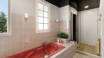 Une salle de bain moderne avec une baignoire rouge, une douche et une fenêtre.