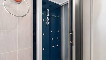 Een badkamer met een blauwe douchecabine, een handdoekhouder en een toilet.