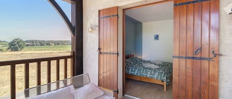 Ein Zimmer mit einem Bett, einer hölzernen Bank und Blick ins Grüne.