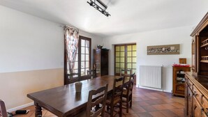 Un comedor con una mesa y sillas de madera, una ventana con vistas y un radiador.
