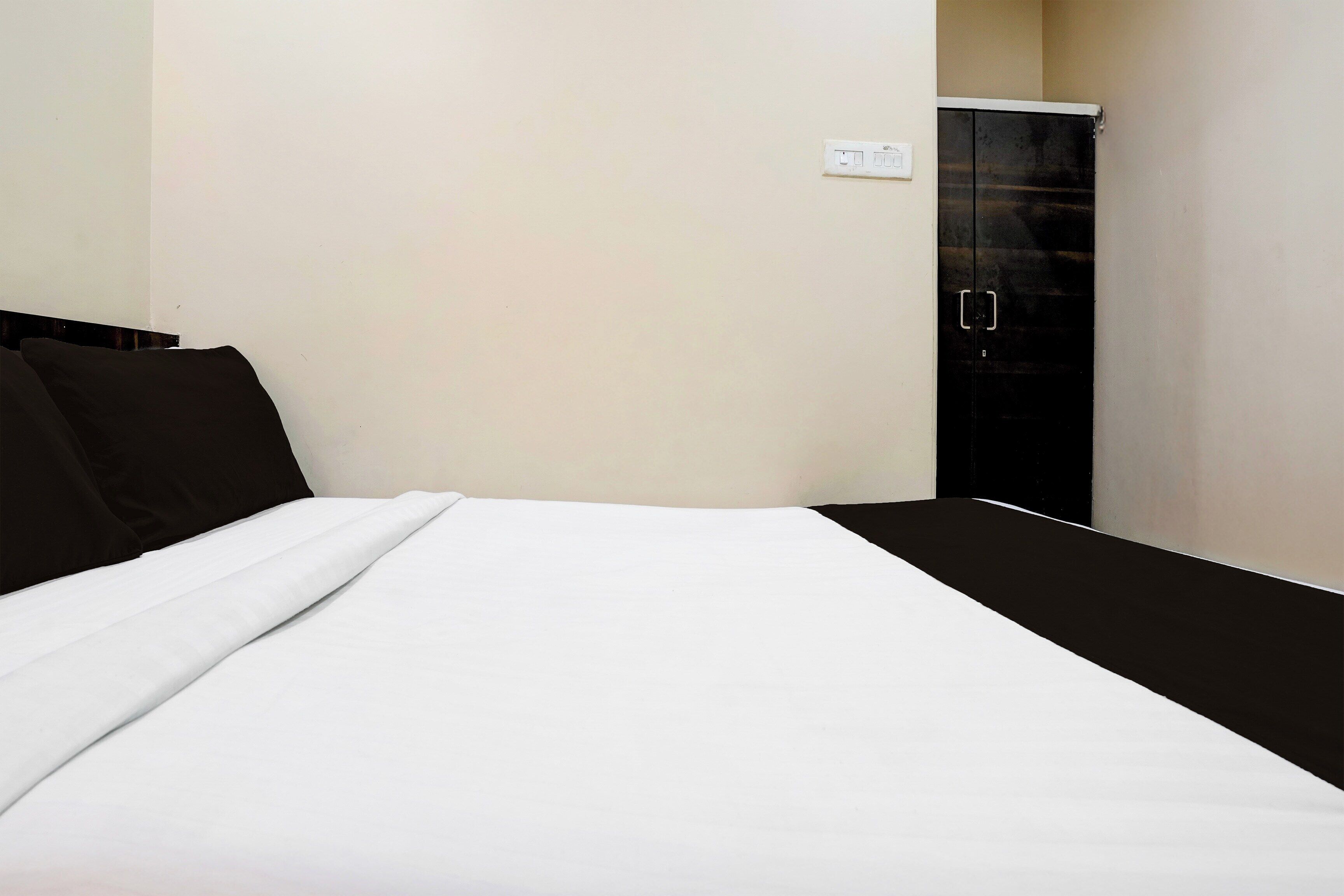 A bed with white bedding, a black headboard, and a single black pillow.