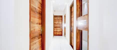 A corridor with wooden doors and a glass window on the right.