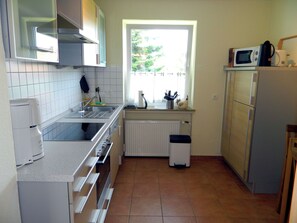 A compact kitchen with a sink, stove, microwave, and a window providing natural light. - Country House Lüneburg Heath – Sleeps up to 6, only 10-min. drive to Heide Park (Neuenkirchen)