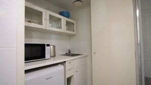 A compact kitchen with a microwave, a small refrigerator, and a sink. - Modern Brisbane Studio in the Heart of CBD (Brisbane)
