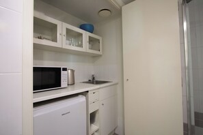 Eine kompakte Küche mit Mikrowelle, kleinem Kühlschrank und Spüle.