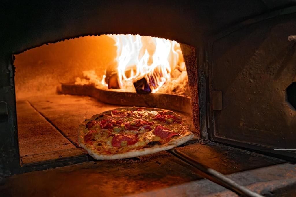 En pizza i en ugn med synliga lågor.