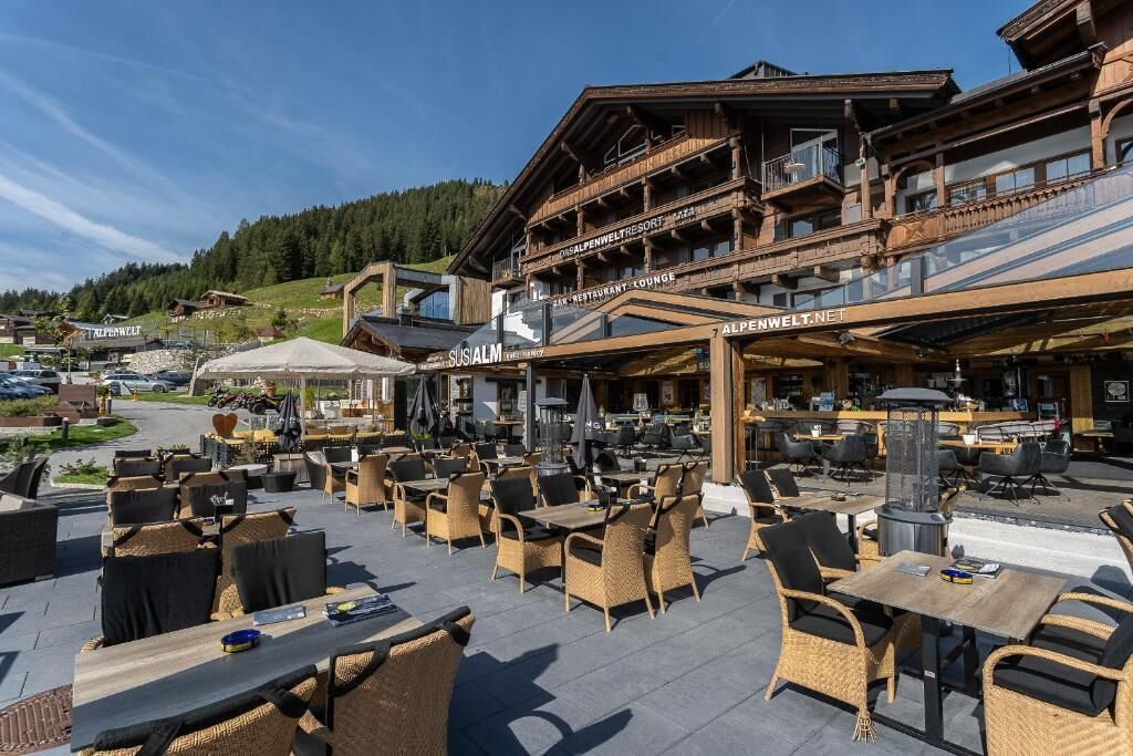 An outdoor seating area with wicker furniture and a bar, surrounded by a wooden building with balconies.