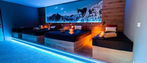 Una habitación moderna con un amplio mural en la pared, asientos integrados e iluminación ambiental.