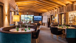 A restaurant with wooden walls, a TV screen, and a welcome sign. - MY ALPENWELT Resort – 4 Sterne Superior (Königsleiten)