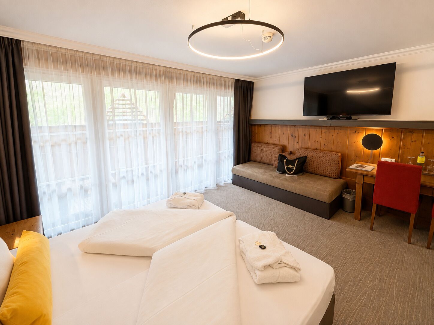 A hotel room with a bed, a sofa, a TV, and a desk.