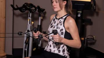 A person using a leg press machine in a gym with exercise equipment in the background.