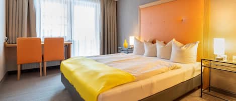 Una habitación de hotel con una cama grande, un escritorio y una silla.