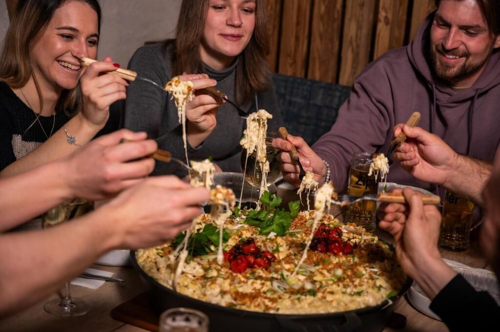 Un gruppo di persone che cena insieme, condividendo un pasto con diversi piatti e bevande.