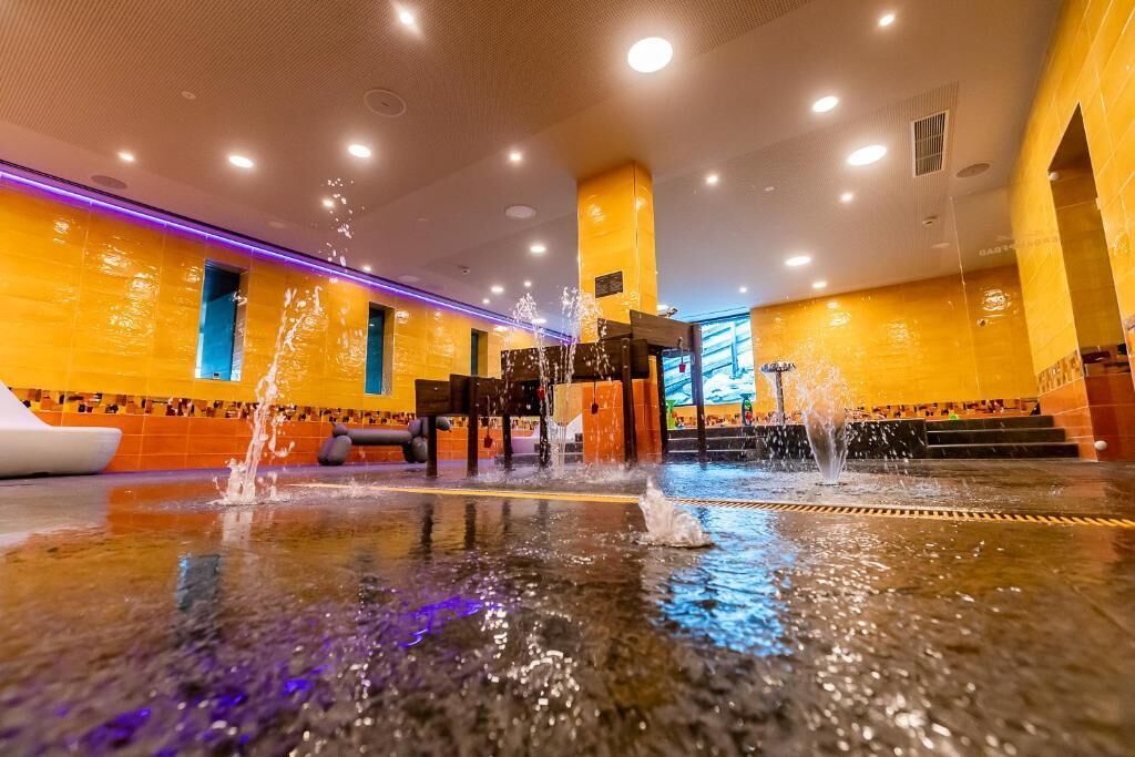 Un hall con fuente de agua, mostrador de recepción y escalera que conduce a un nivel superior.