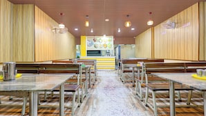En restaurantindretning med træpaneler, flere borde og bænke samt en central disk med en menukort.