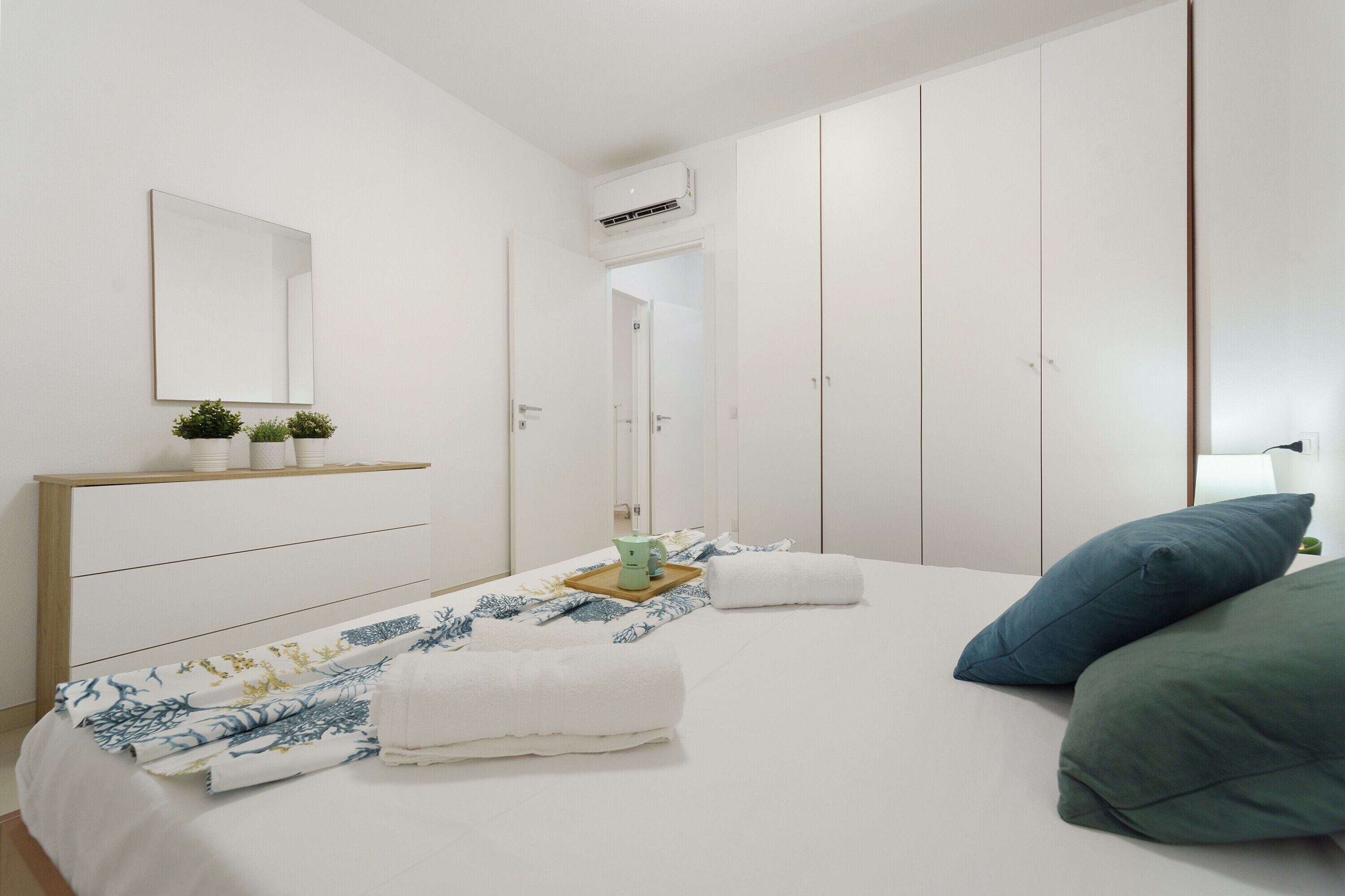 Un dormitorio con cama, mesita de noche, espejo y armario.