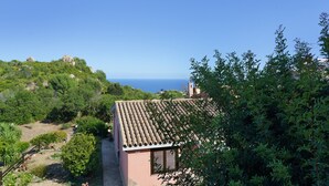 A coastal property with a terracotta roof, surrounded by lush greenery and overlooking the sea. - Costa Rei – Delightful Apartment with Garden (Muravera)