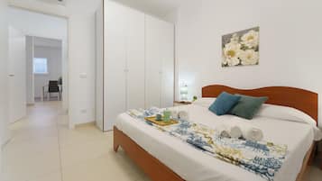 Un dormitorio con cama, mesita de noche, cuadro y puerta que da a otra habitación.