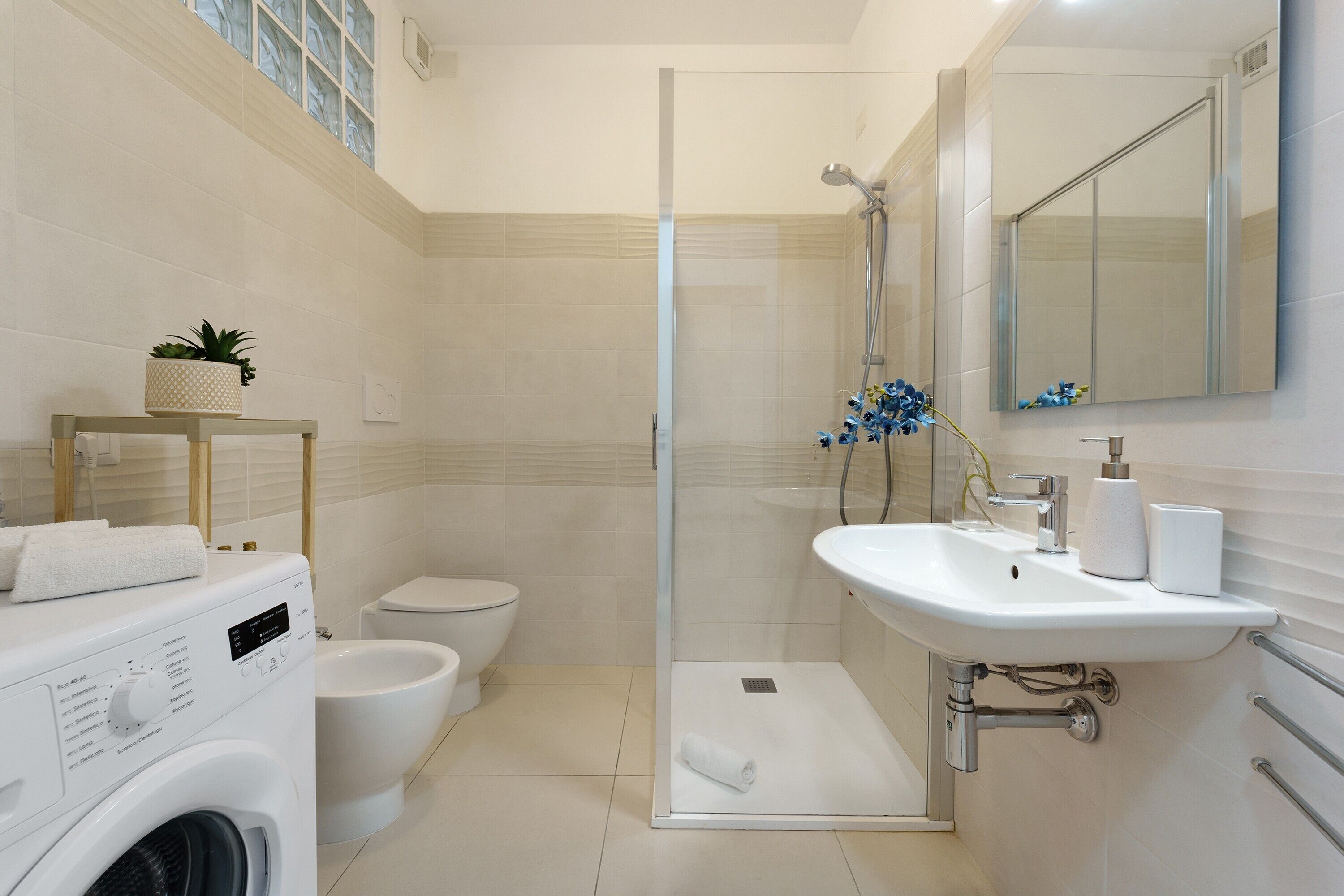 Ein modernes Badezimmer mit einer gläsernen Dusche, einem weißen Waschbecken und einer Toilette.