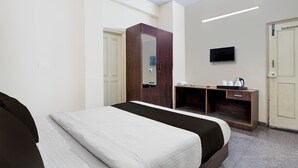 Ett hotellrum med en säng, ett skrivbord, en tv och en garderob.