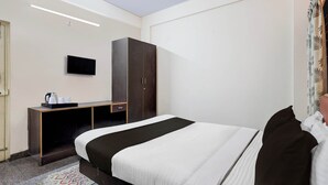 Ett hotellrum med en säng, en garderob, ett skrivbord med en platt-TV och en kaffemaskin.