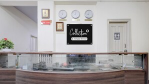 Ett receptionsområde med ett glasmontrinskåp, klockor som visar olika tidszoner och en skylt med texten ”Service utförd av inkassobolaget”.