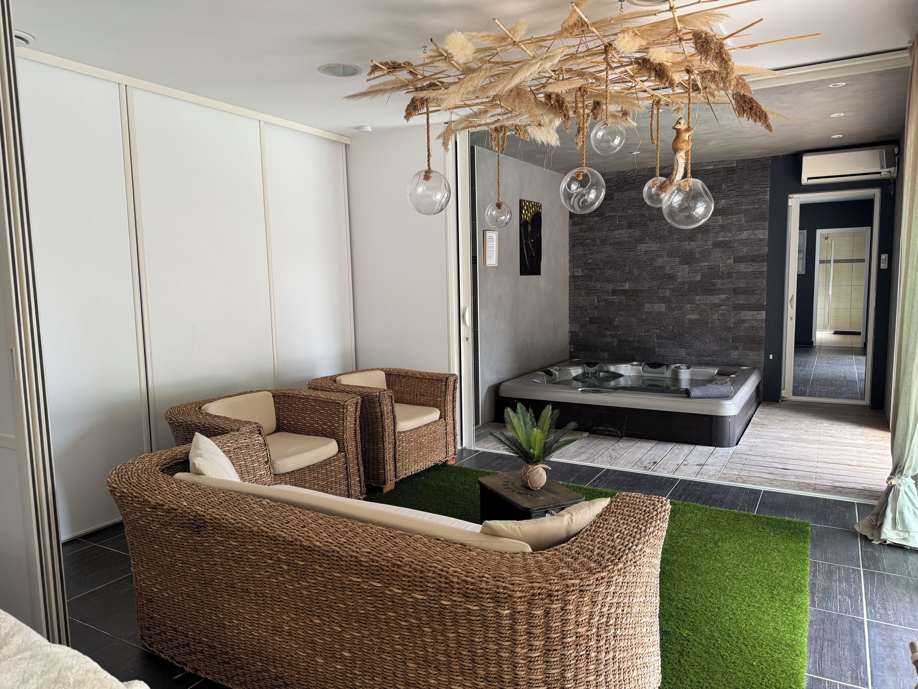 A modern living area with a wicker sofa, a glass-top coffee table, and a decorative ceiling feature.