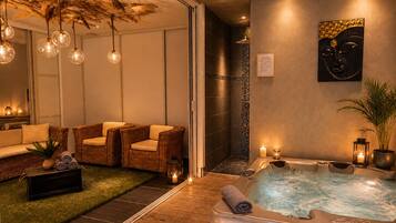 A spa area with a hot tub, wicker chairs, a massage table, and a wall-mounted artwork.